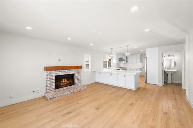 25311 Misty Rdg, Mission Viejo, CA 92692 - unfurnished living room with light wood-style floors, baseboards, recessed lighting, a brick fireplace, and a sink