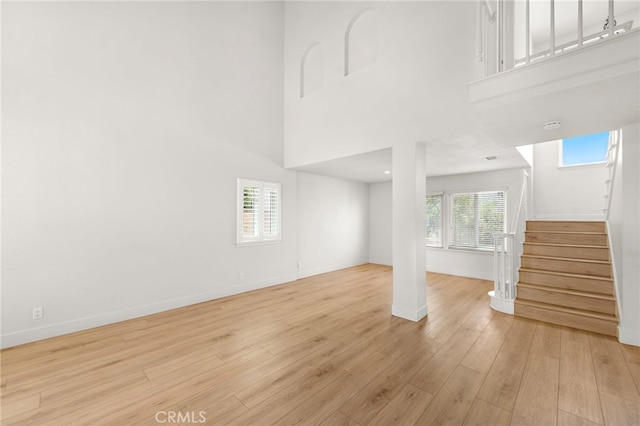 25311 Misty Rdg, Mission Viejo, CA 92692 - unfurnished living room featuring stairs, baseboards, a towering ceiling, and light wood-style floors