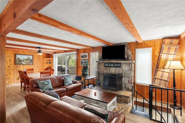 233 Glen Avon Dr, Cedar Glen, CA 92321 - living area featuring wooden walls, wood finished floors, a stone fireplace, beamed ceiling, and a ceiling fan