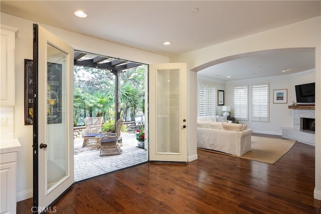 114 Via Monte Picayo, San Clemente, CA 92673 - doorway to outside featuring arched walkways, dark wood finished floors, a fireplace with raised hearth, crown molding, and baseboards