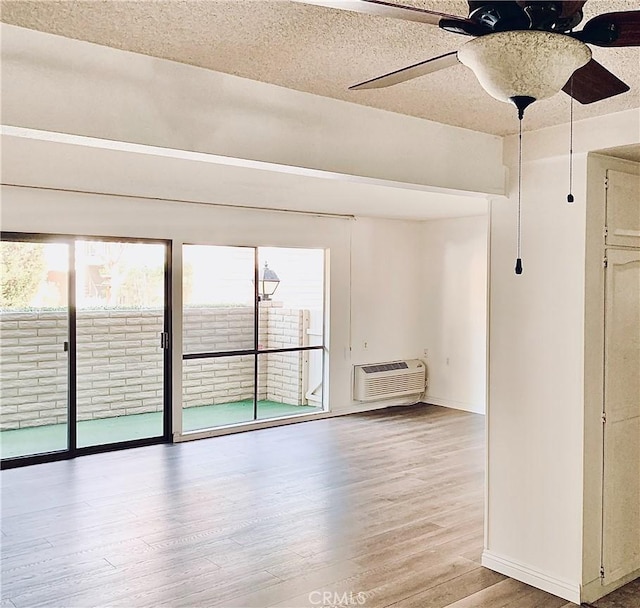 897 Ronda Sevilla C, Laguna Woods, CA 92637 - unfurnished room with ceiling fan, an AC wall unit, wood finished floors, and a textured ceiling