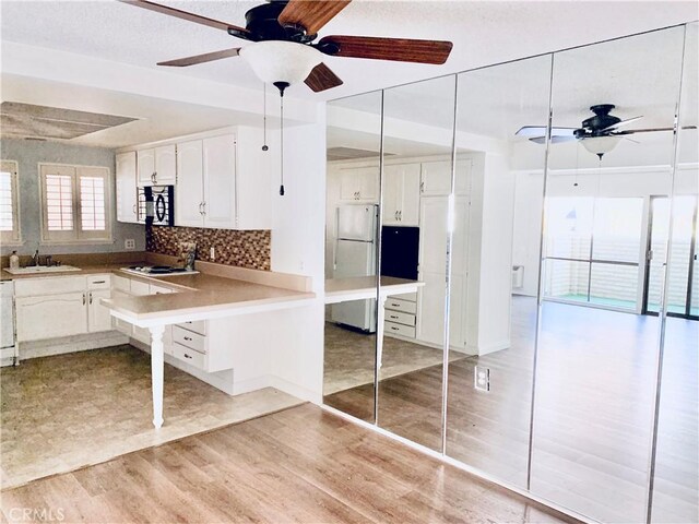897 Ronda Sevilla C, Laguna Woods, CA 92637 - kitchen with ceiling fan, white appliances, light wood-type flooring, white cabinets, and tasteful backsplash