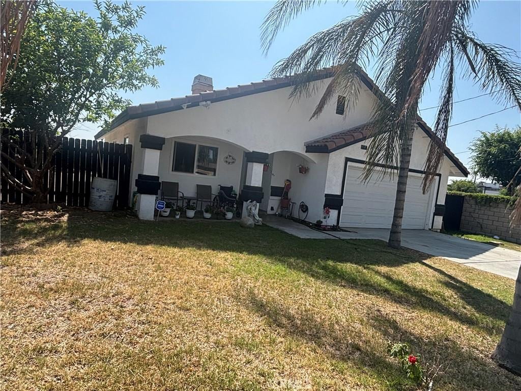 3360 Winstrom St, Riverside, CA 92504 - rear view of property featuring stucco siding, concrete driveway, a chimney, an attached garage, and a tile roof