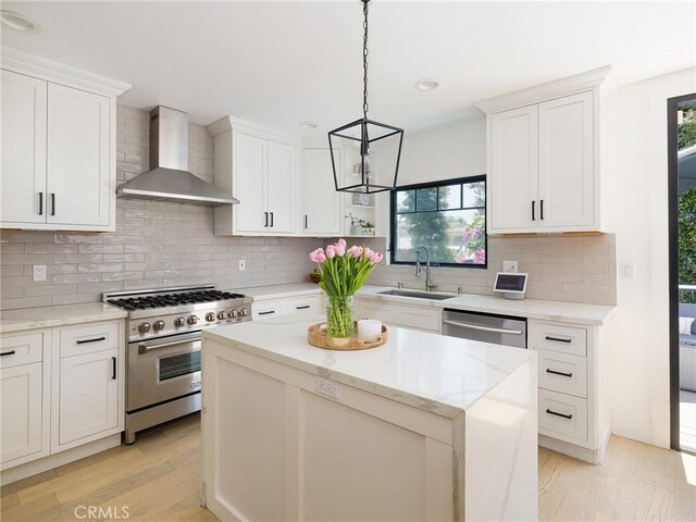 618 W Elm Ave, El Segundo, CA 90245 - kitchen with stainless steel appliances, wall chimney range hood, a sink, light wood-style floors, and a center island