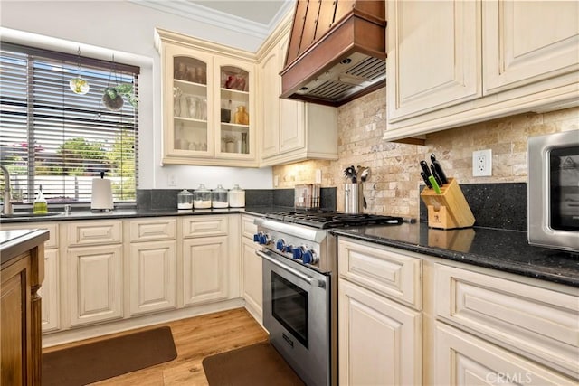 42302 Oregon Trl, Murrieta, CA 92562 - kitchen with stainless steel appliances, premium range hood, cream cabinetry, ornamental molding, and a sink
