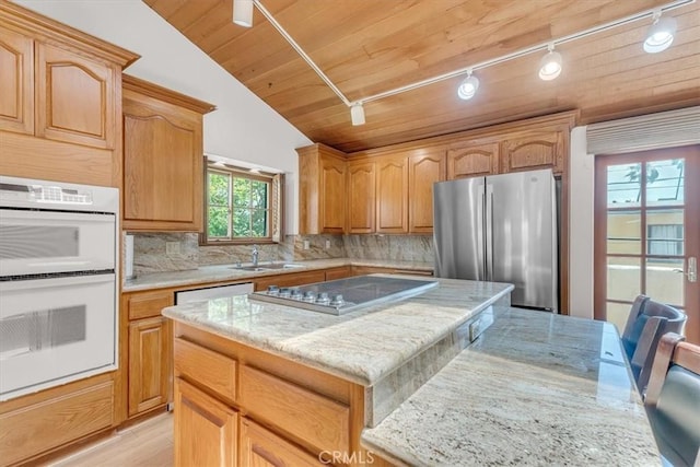 1110 Esplanade Unit 6, Redondo Beach, CA 90277 - kitchen featuring appliances with stainless steel finishes, track lighting, light stone countertops, tasteful backsplash, and a kitchen island