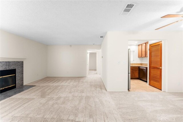 8313 Vineyard Ave # 6, Rancho Cucamonga, CA 91730 - unfurnished living room featuring light carpet, a tiled fireplace, a textured ceiling, ceiling fan, and baseboards