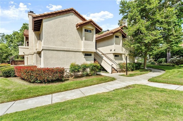 8313 Vineyard Ave # 6, Rancho Cucamonga, CA 91730 - view of side of home featuring a lawn, stairway, stucco siding, a tile roof, and a chimney