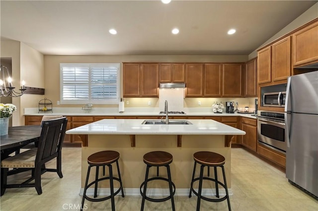 5058 Meadowsweet Dr, Palmdale, CA 93551 - kitchen with appliances with stainless steel finishes, under cabinet range hood, a sink, light countertops, and an island with sink