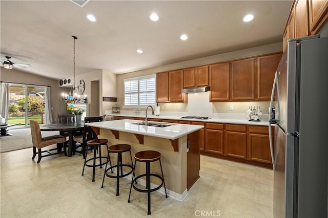5058 Meadowsweet Dr, Palmdale, CA 93551 - kitchen with freestanding refrigerator, a sink, under cabinet range hood, brown cabinets, and gas cooktop