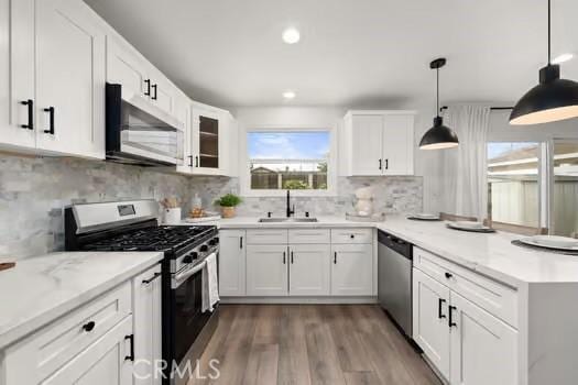 10946 Kentucky Ave, Whittier, CA 90603 - kitchen featuring stainless steel appliances, a sink, a peninsula, wood finished floors, and white cabinets