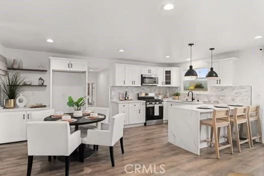 10946 Kentucky Ave, Whittier, CA 90603 - kitchen with appliances with stainless steel finishes, a peninsula, white cabinetry, decorative backsplash, and a sink