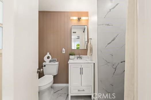 10946 Kentucky Ave, Whittier, CA 90603 - full bath featuring marble look tiles, toilet, vanity, wood walls, and a shower