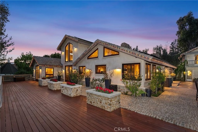 7626 E Saddlehill Trl, Orange, CA 92869 - back of house at dusk featuring a deck, stucco siding, and a fire pit