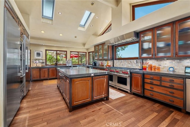 7626 E Saddlehill Trl, Orange, CA 92869 - kitchen with high end appliances, a skylight, dark countertops, a sink, and hardwood / wood-style floors