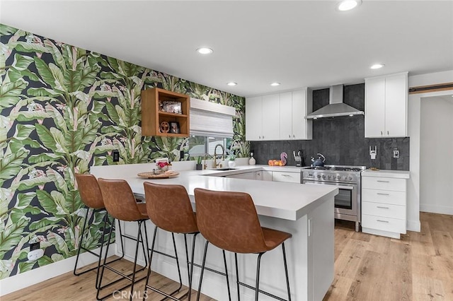 6324 E Colorado St, Long Beach, CA 90803 - kitchen with wall chimney exhaust hood, stainless steel stove, a breakfast bar, a peninsula, and light countertops