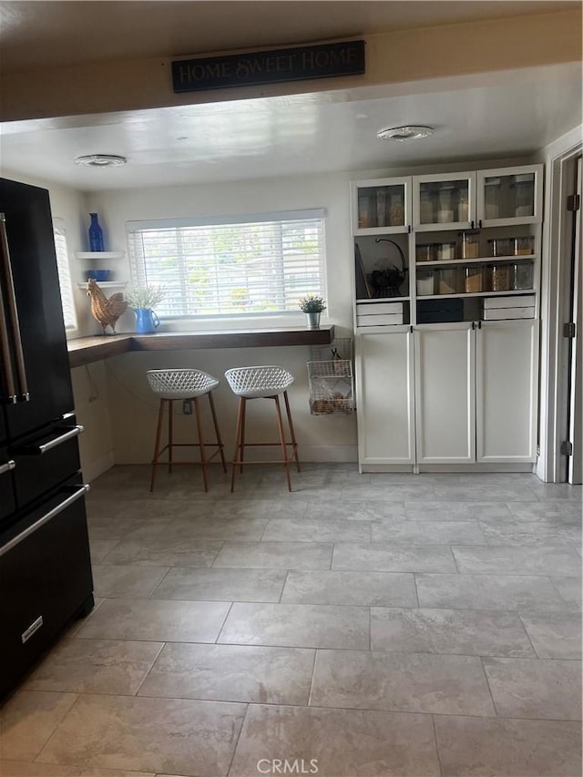 1767 W Chandeleur Dr, San Pedro, CA 90732 - kitchen with freestanding refrigerator, open shelves, a kitchen bar, and glass insert cabinets