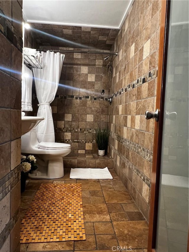 1767 W Chandeleur Dr, San Pedro, CA 90732 - bathroom featuring tiled shower, stone tile flooring, toilet, and tile walls