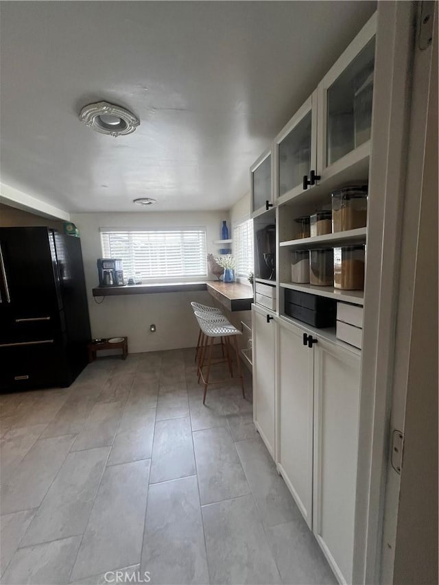 1767 W Chandeleur Dr, San Pedro, CA 90732 - kitchen with freestanding refrigerator, open shelves, light countertops, light tile patterned flooring, and white cabinets