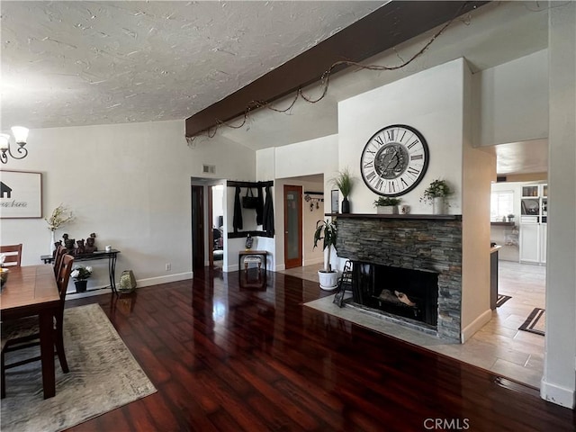 1767 W Chandeleur Dr, San Pedro, CA 90732 - living room with wood finished floors, a textured ceiling, baseboards, a stone fireplace, and a chandelier