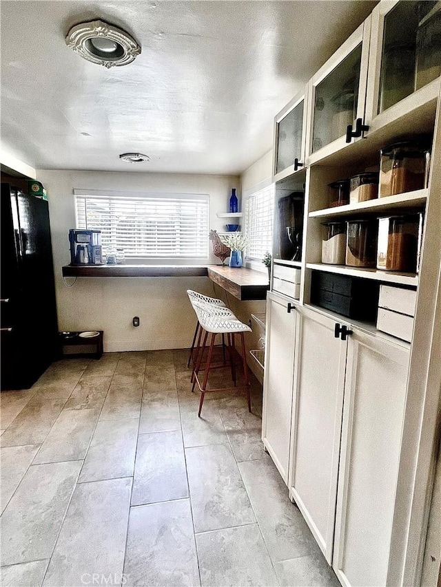 1767 W Chandeleur Dr, San Pedro, CA 90732 - kitchen featuring open shelves, glass insert cabinets, freestanding refrigerator, and light tile patterned floors