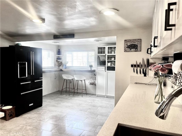 1767 W Chandeleur Dr, San Pedro, CA 90732 - kitchen featuring black fridge with ice dispenser, white cabinets, and light stone countertops