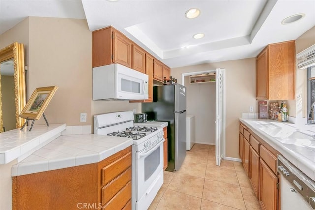 56 Coventry Ln Unit 293, Aliso Viejo, CA 92656 - kitchen featuring white appliances, a tray ceiling, recessed lighting, light tile patterned floors, and brown cabinets