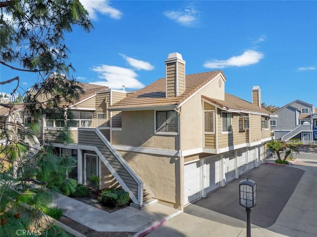 56 Coventry Ln Unit 293, Aliso Viejo, CA 92656 - back of house with a chimney, stucco siding, stairway, a residential view, and a tile roof