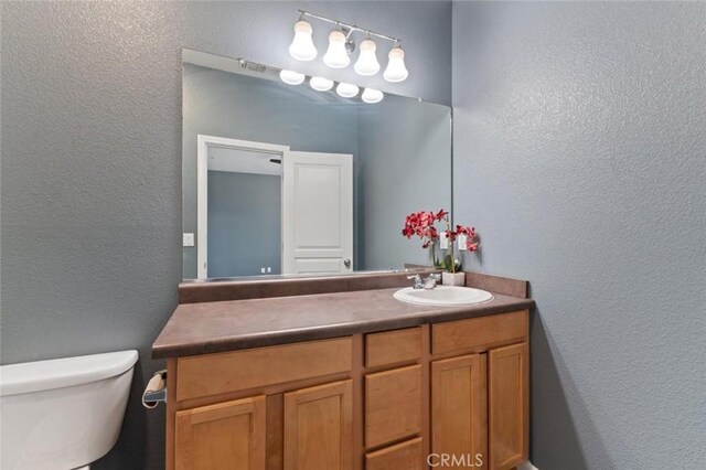 1171 S Filbert Ave, Fresno, CA 93727 - bathroom featuring a textured wall, vanity, and toilet