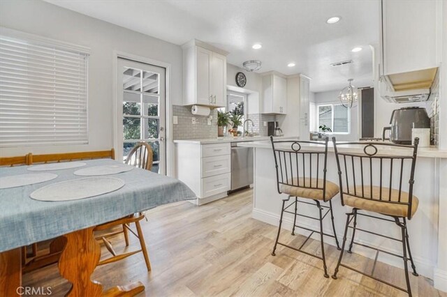 11025 Shaw St, Rancho Cucamonga, CA 91701 - kitchen with stainless steel dishwasher, white cabinetry, a breakfast bar area, light wood finished floors, and light countertops
