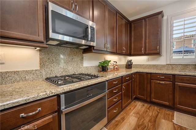 34197 Helenium St, Murrieta, CA 92563 - kitchen featuring stainless steel appliances, light wood finished floors, light stone countertops, backsplash, and dark brown cabinetry