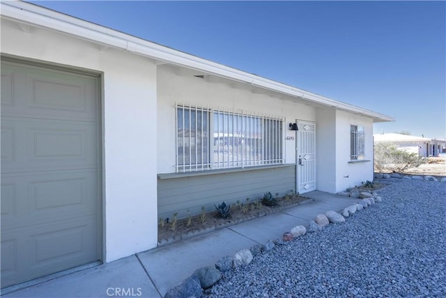 66691 Flora Ave, Desert Hot Springs, CA 92240 - view of exterior entry featuring a garage and stucco siding