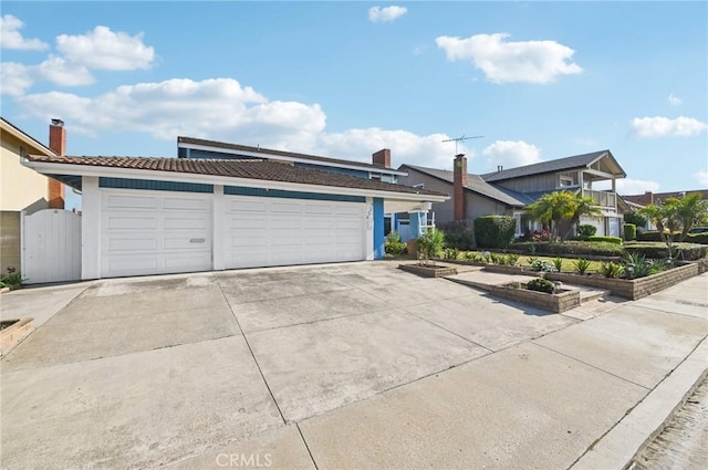 9256 Crocus Ave, Fountain Valley, CA 92708 - view of front of house with concrete driveway, a garage, a tiled roof, stucco siding, and a garden