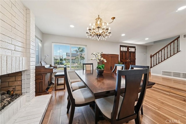 9256 Crocus Ave, Fountain Valley, CA 92708 - dining space with wood-type flooring, stairway, a chandelier, recessed lighting, and a brick fireplace
