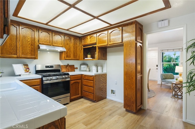1357 Curtis Ave, Manhattan Beach, CA 90266 - kitchen featuring gas range, under cabinet range hood, brown cabinetry, light wood finished floors, and tile counters