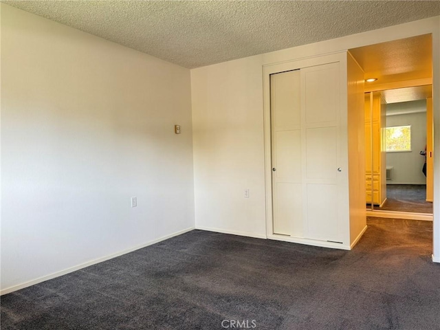 680 Via Alhambra Unit O, Laguna Woods, CA 92637 - unfurnished bedroom featuring dark carpet, a textured ceiling, baseboards, and a closet