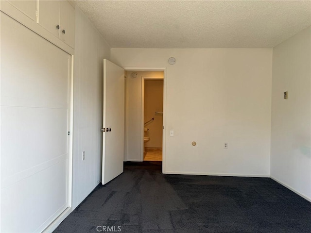 680 Via Alhambra Unit O, Laguna Woods, CA 92637 - unfurnished room with dark carpet, a textured ceiling, and baseboards