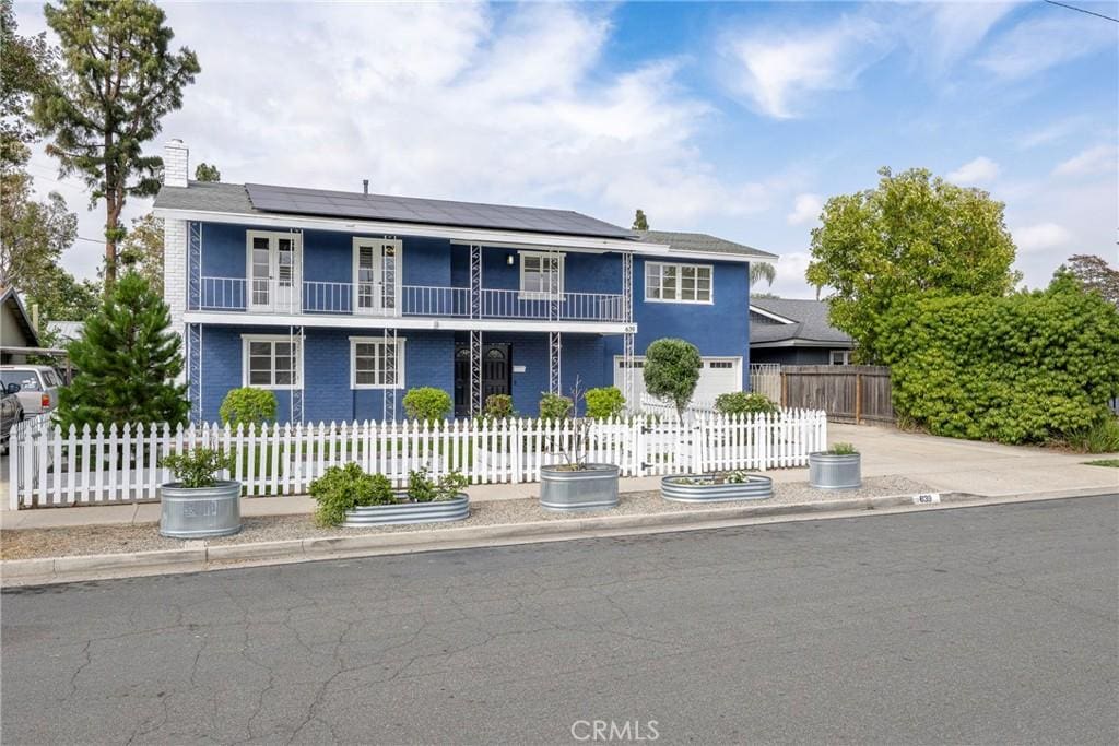 639 Royal Stewart, Placentia, CA 92870 - front of property with a balcony, roof mounted solar panels, a fenced front yard, and a chimney