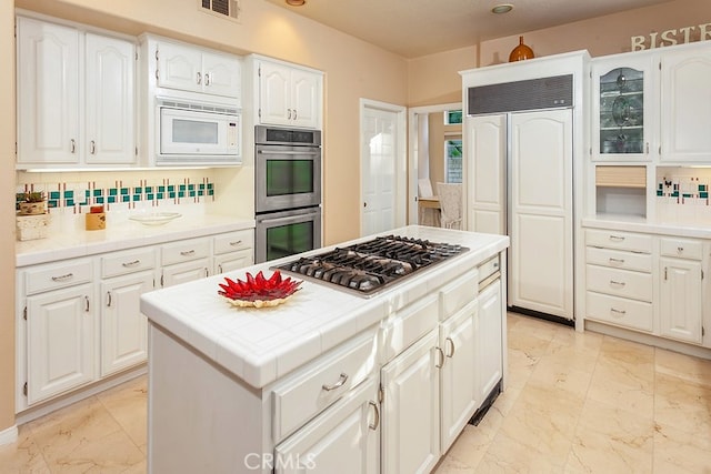 17910 Montague Ct, Granada Hills, CA 91344 - kitchen with built in appliances, light marble finish floors, white cabinets, and tile countertops