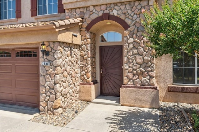 7538 N Erie Ave, Fresno, CA 93722 - view of exterior entry with stone siding and a garage