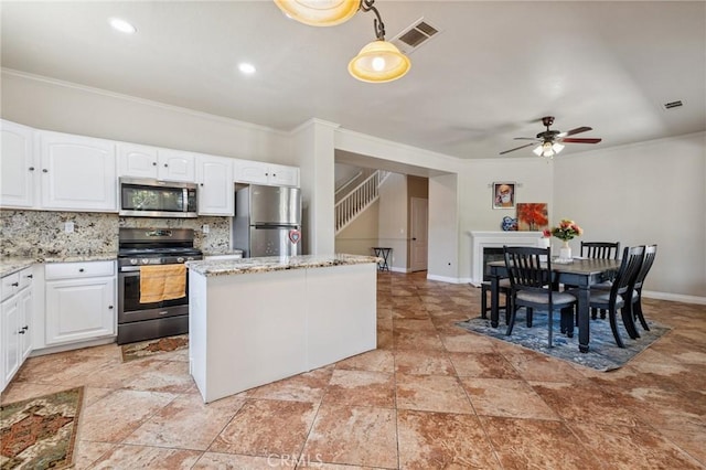 7538 N Erie Ave, Fresno, CA 93722 - kitchen with stainless steel appliances, crown molding, a kitchen island, a ceiling fan, and decorative backsplash
