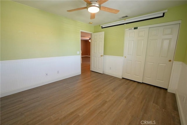 29429 Masters Dr, Murrieta, CA 92563 - unfurnished bedroom featuring wainscoting, wood finished floors, a closet, and a ceiling fan