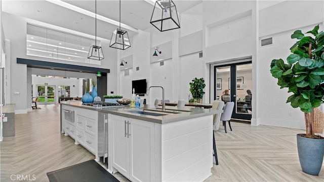 2123 Scholarship, Irvine, CA 92612 - kitchen with a sink, french doors, open floor plan, a center island with sink, and white cabinetry