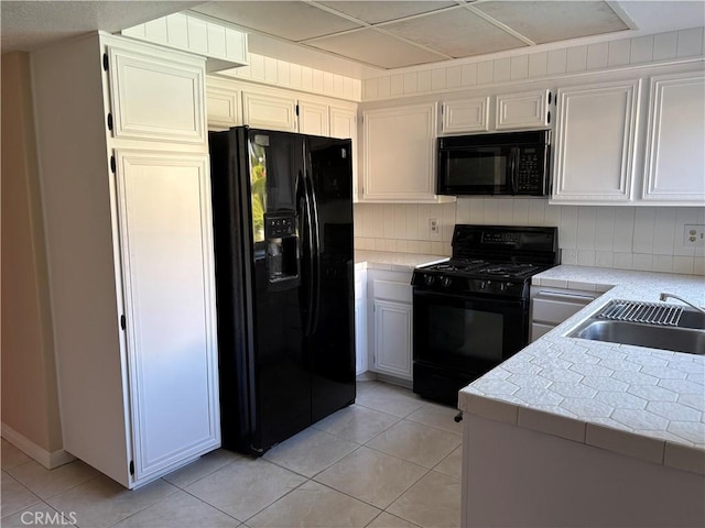 7950 Gardenia, Rancho Cucamonga, CA 91701 - kitchen with black appliances, light tile patterned flooring, tile counters, and white cabinetry