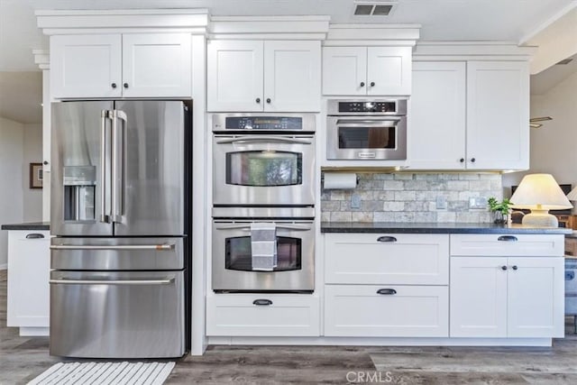 12355 Santa Ana Rd, Atascadero, CA 93422 - kitchen featuring appliances with stainless steel finishes, wood finished floors, white cabinets, and decorative backsplash