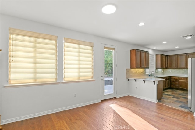 211 Furyk Way, Hemet, CA 92545 - kitchen featuring a breakfast bar area, light wood finished floors, light countertops, tasteful backsplash, and a peninsula