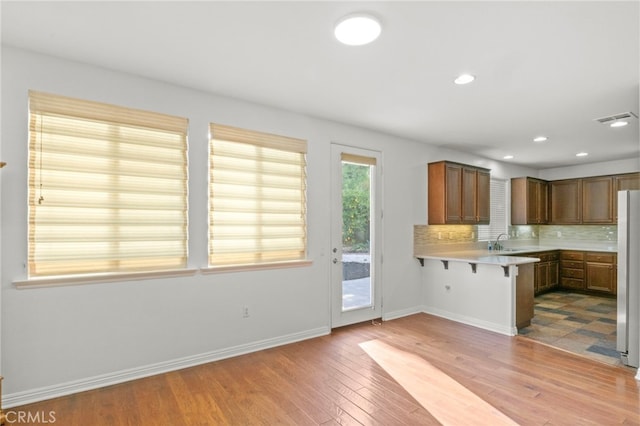211 Furyk Way, Hemet, CA 92545 - kitchen with a breakfast bar area, light wood-style floors, light countertops, backsplash, and a peninsula