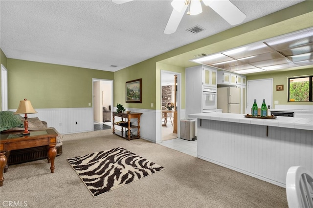 2380 Peppertree Ln, Riverside, CA 92506 - kitchen with tile counters, light carpet, white appliances, glass insert cabinets, and a wainscoted wall