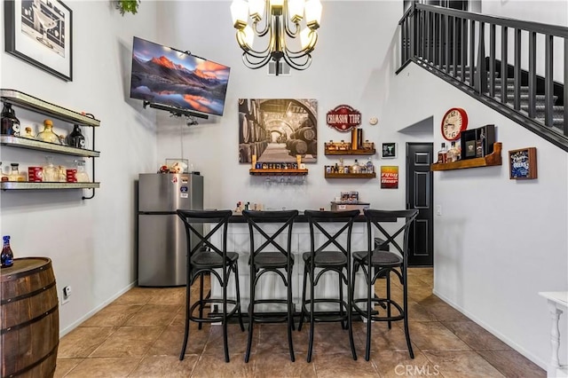 3568 Rock Butte Pl, Perris, CA 92570 - indoor wet bar with freestanding refrigerator, a chandelier, baseboards, a towering ceiling, and tile patterned flooring