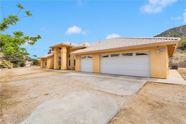 1679 Desert Front Rd, Wrightwood, CA 92397 - mediterranean / spanish-style home with a tiled roof, stucco siding, a garage, and cooling unit